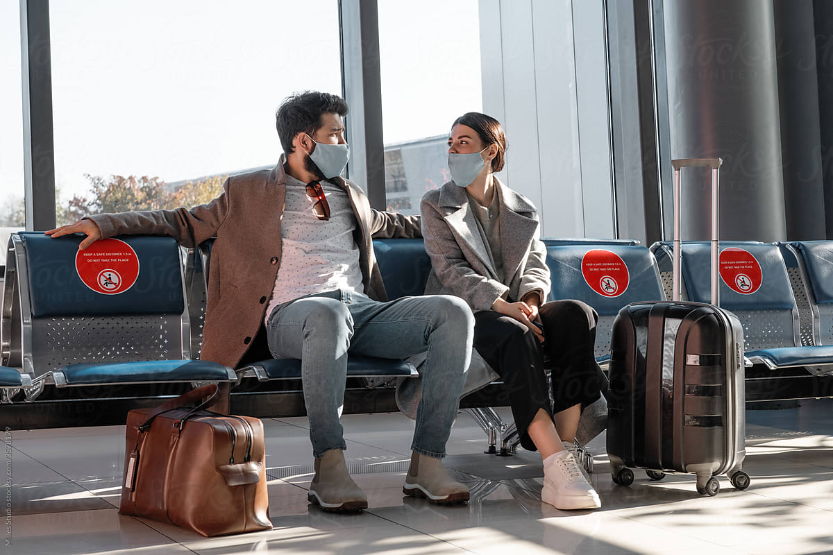 Couple in masks talking in airport waiting room