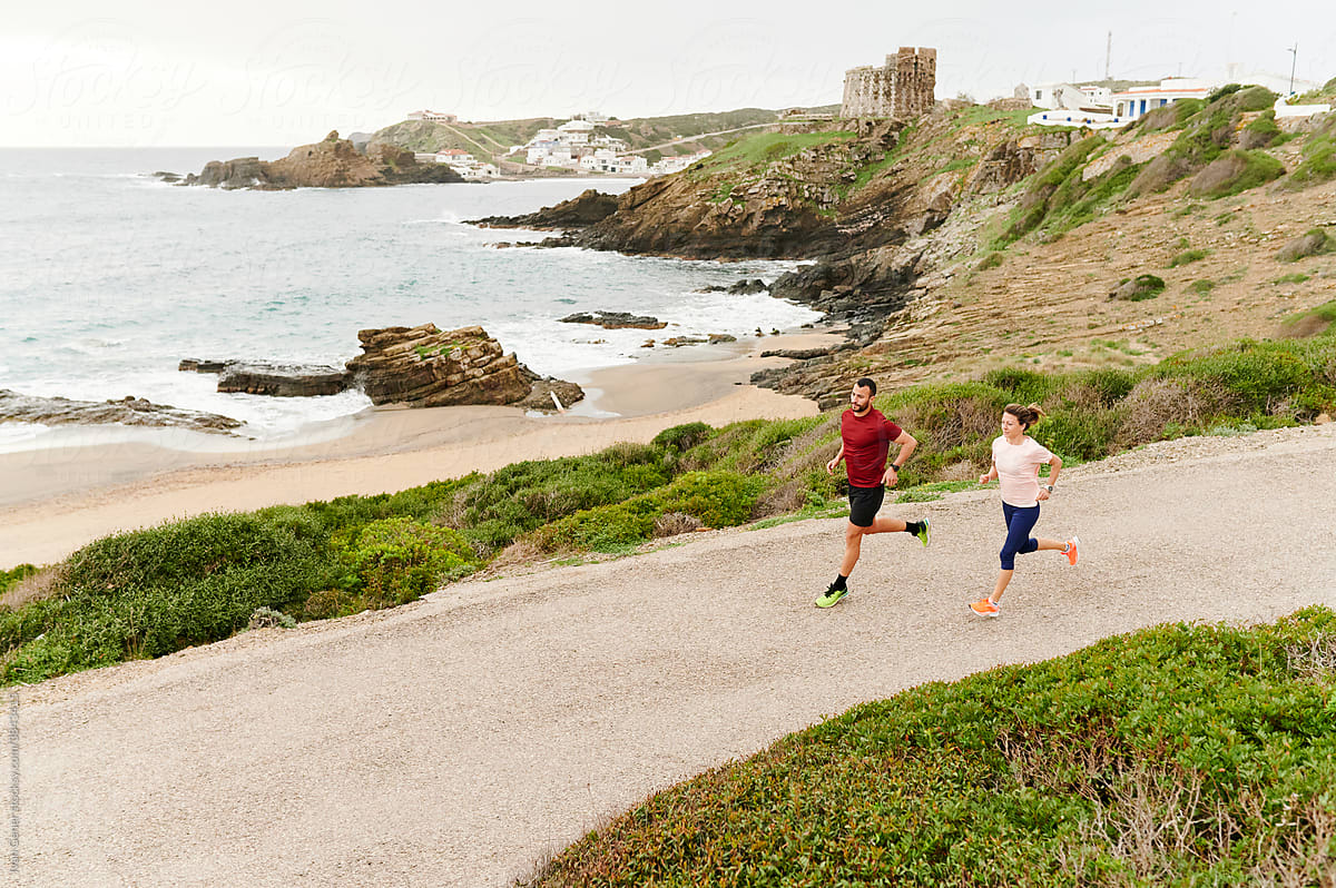 Couple out running on a road by the ocean