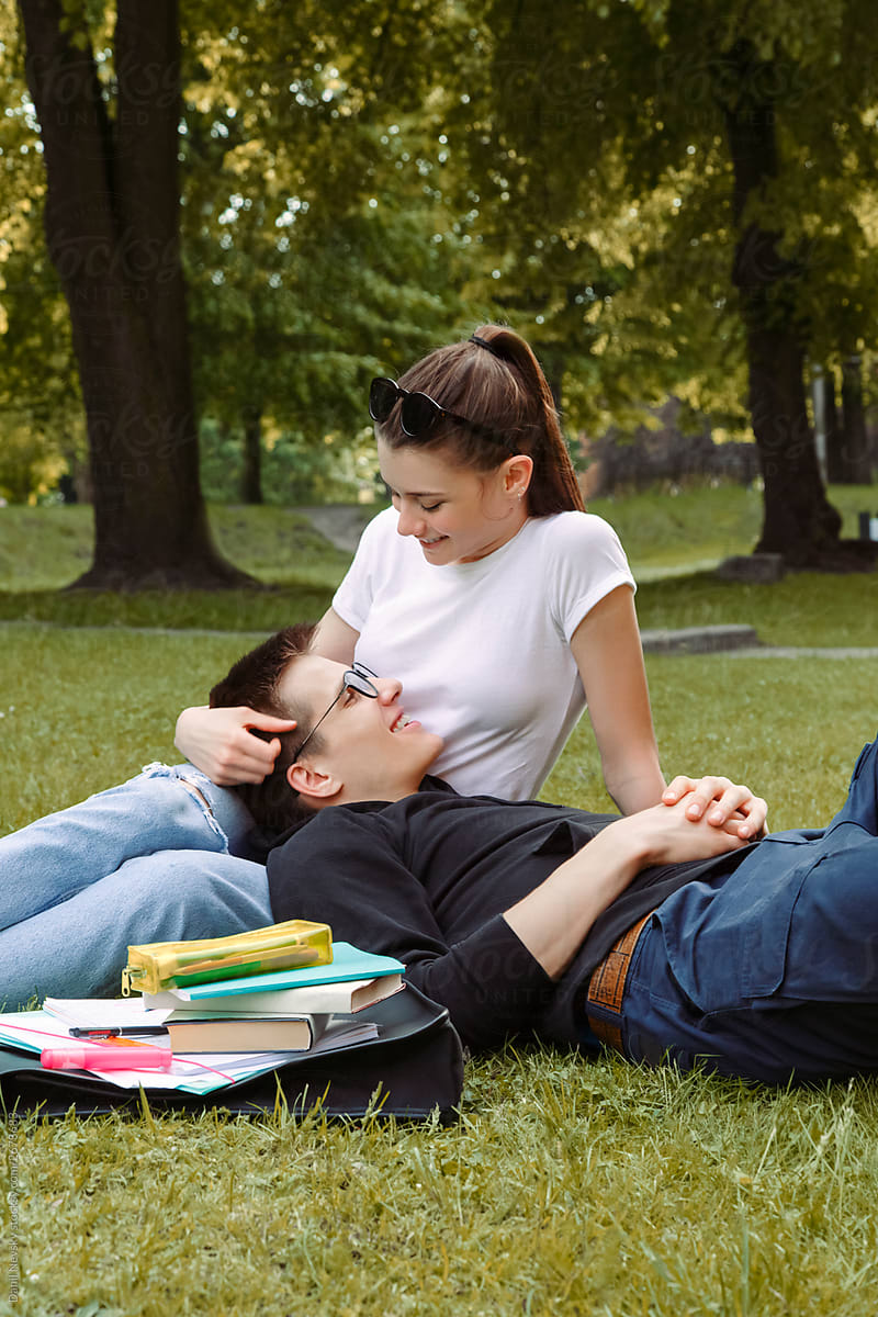 couple of students in love lies on the grass in the park