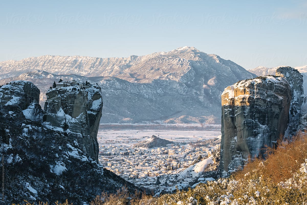 meteora in winter at sunrise with the city of kalambaka in the back