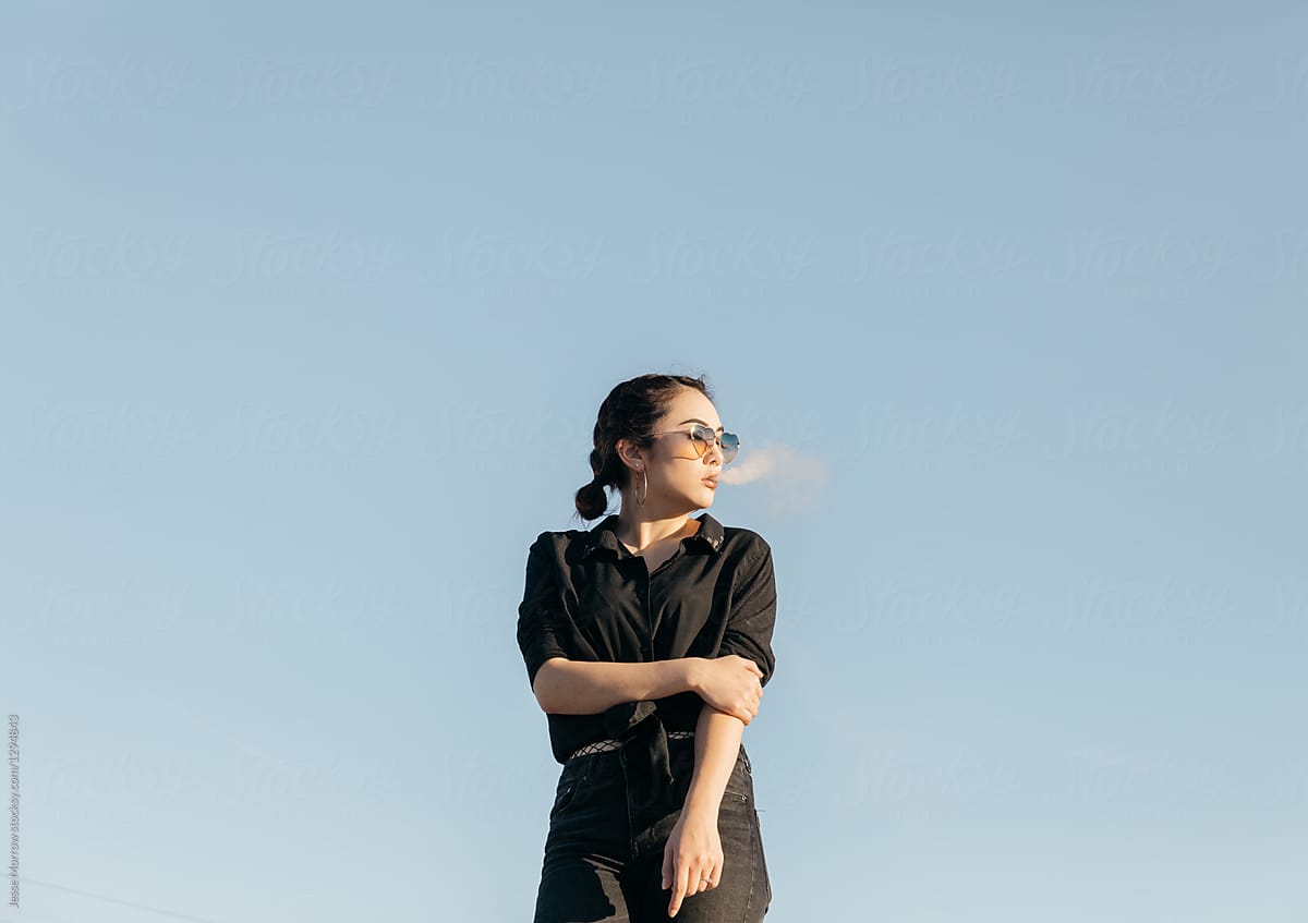young woman smoking with cloud puff smoke in front of face