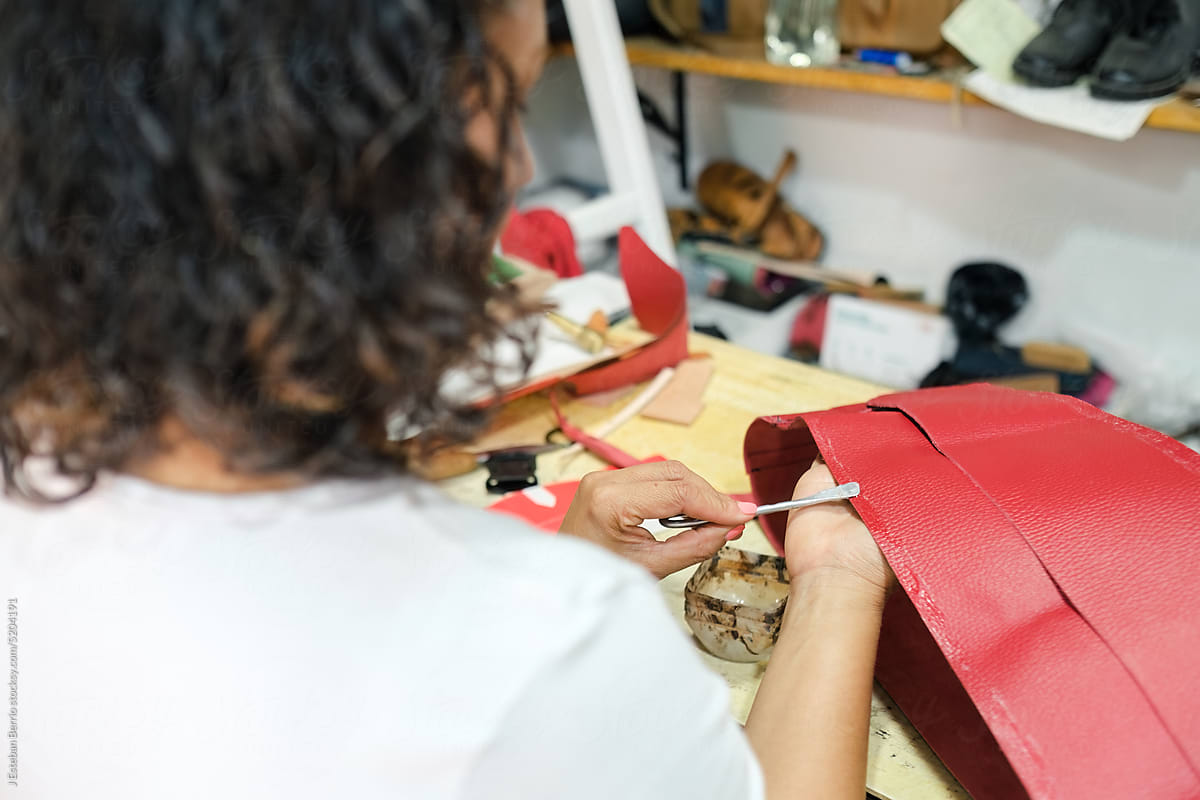 Craftswoman applying glue to a piece of leather.