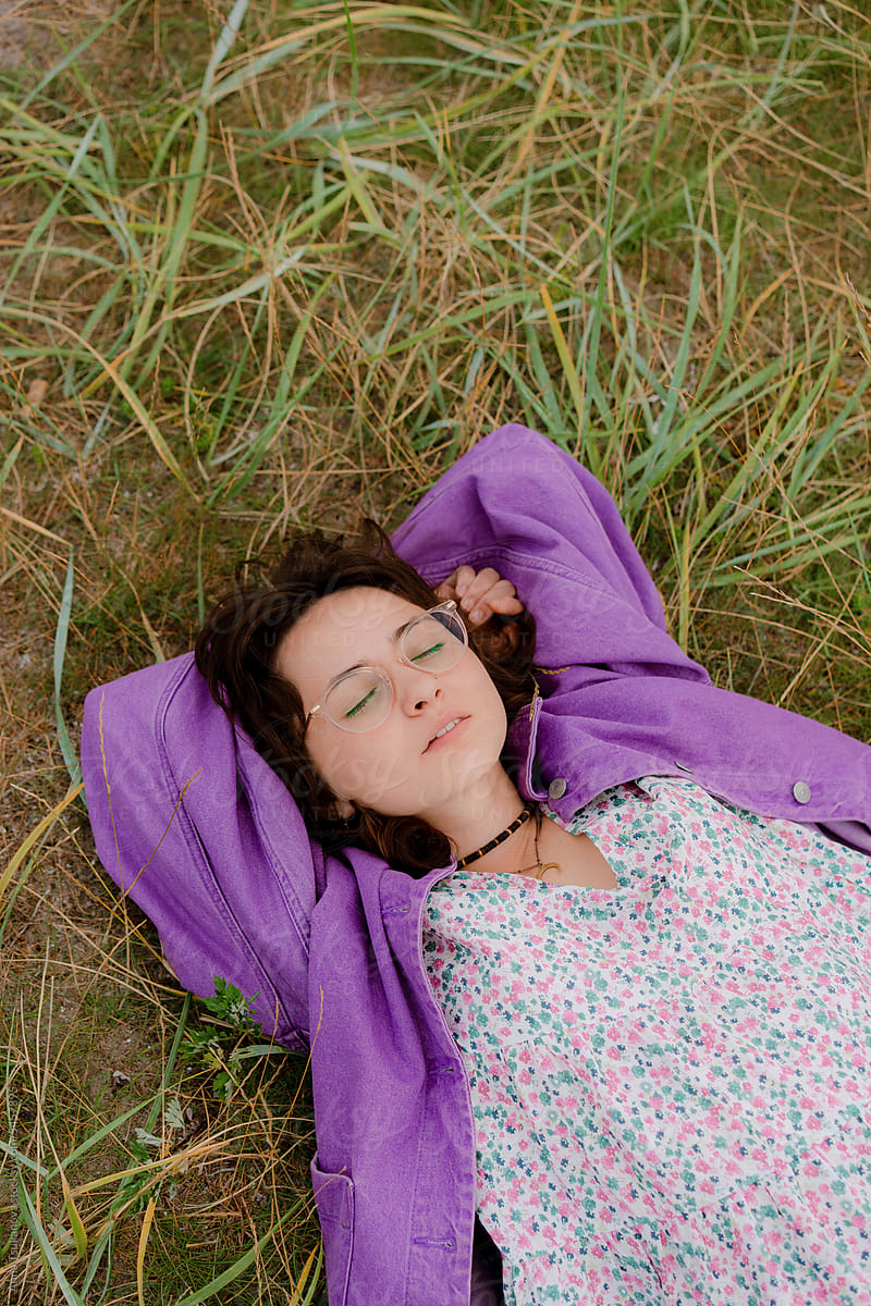 Woman in eyeglasses laying on grass