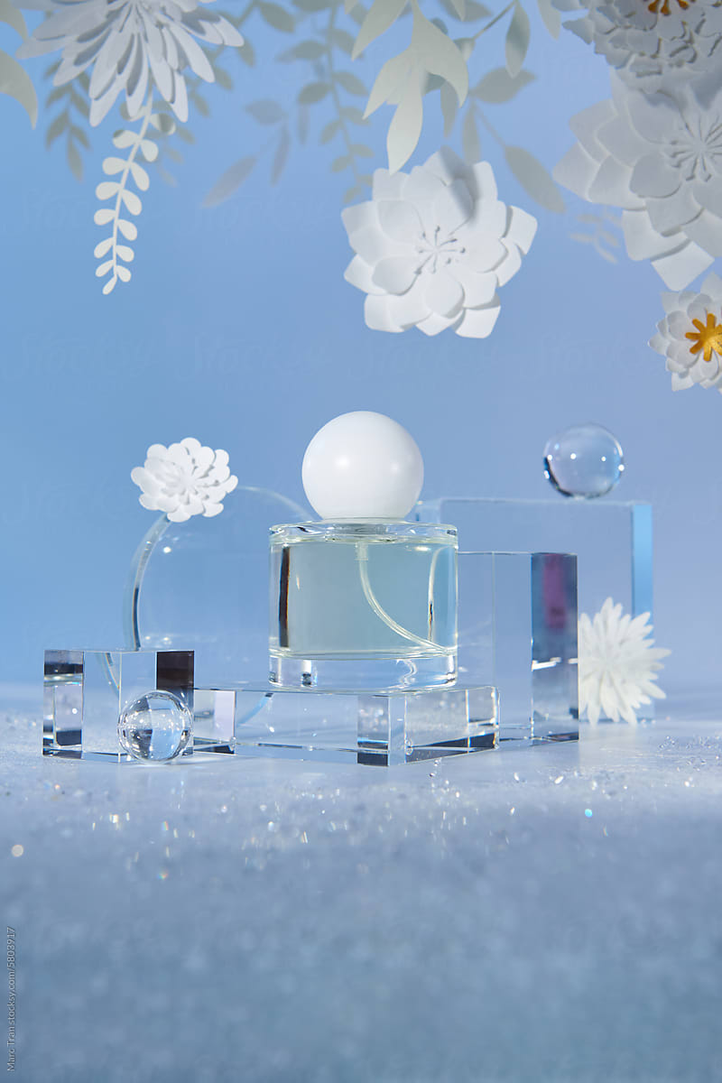 Transparent fragrance bottle on glass block on sparkling