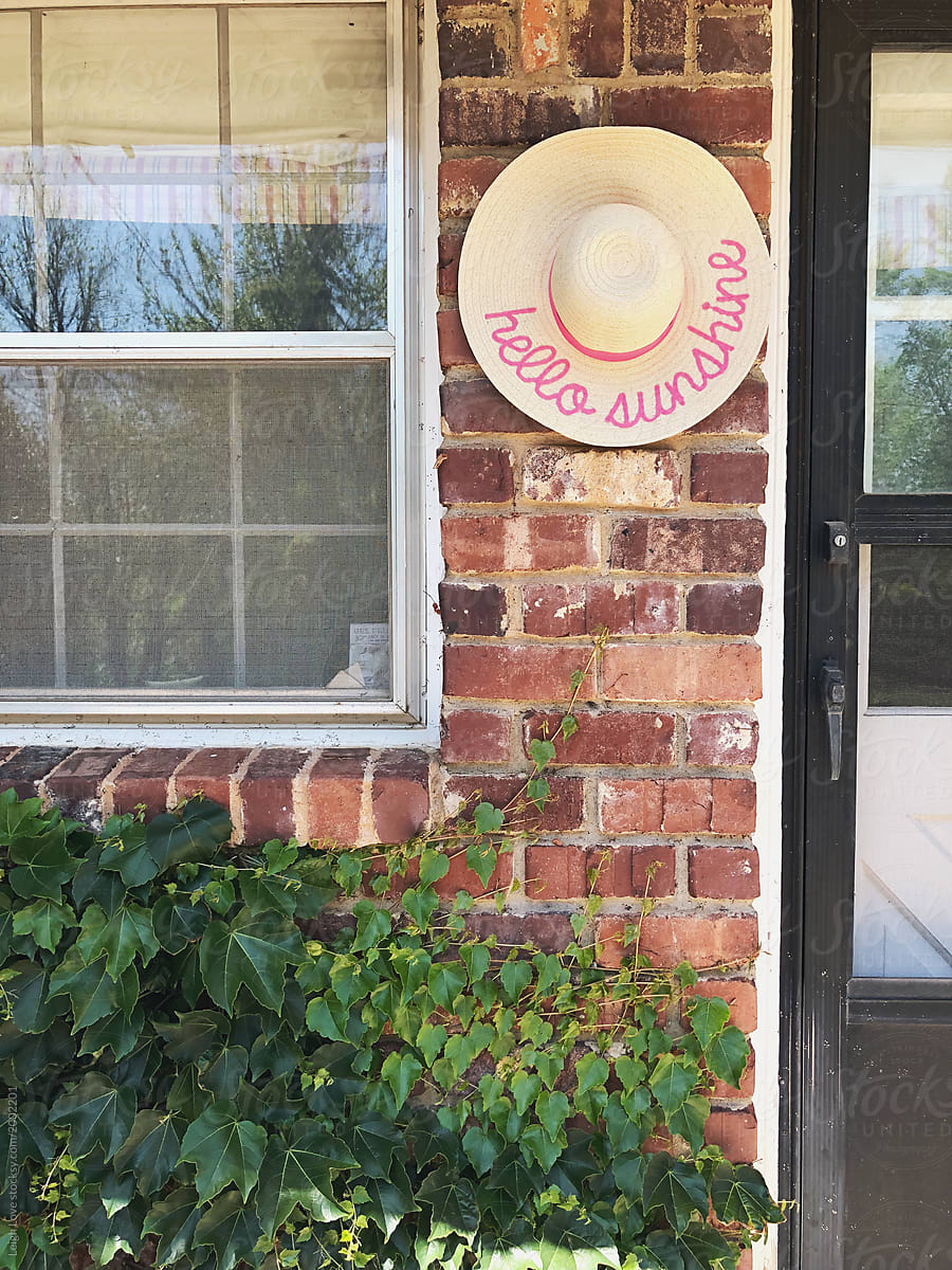 Hello Sunshine Hat Hanging on Brick Outdoor Ivy Covered Wall
