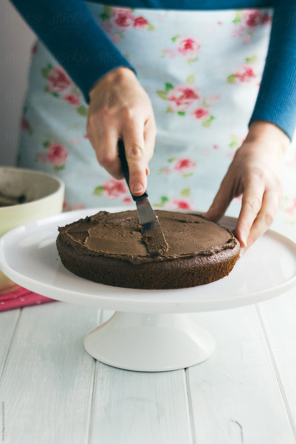 Woman spreading chocolate buttercream onto cake
