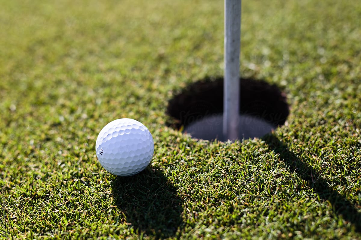 Golf ball near hole on putting green