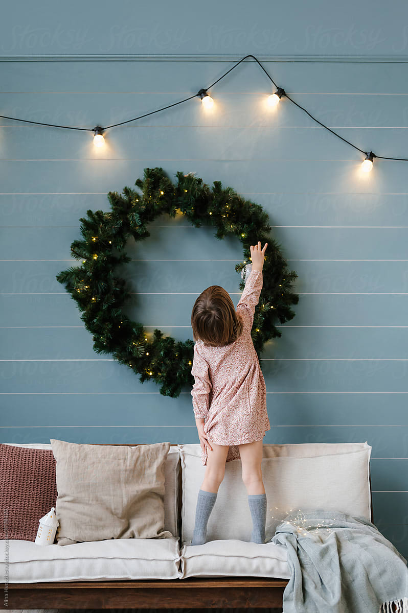 Girl decorating fir wreath on wall
