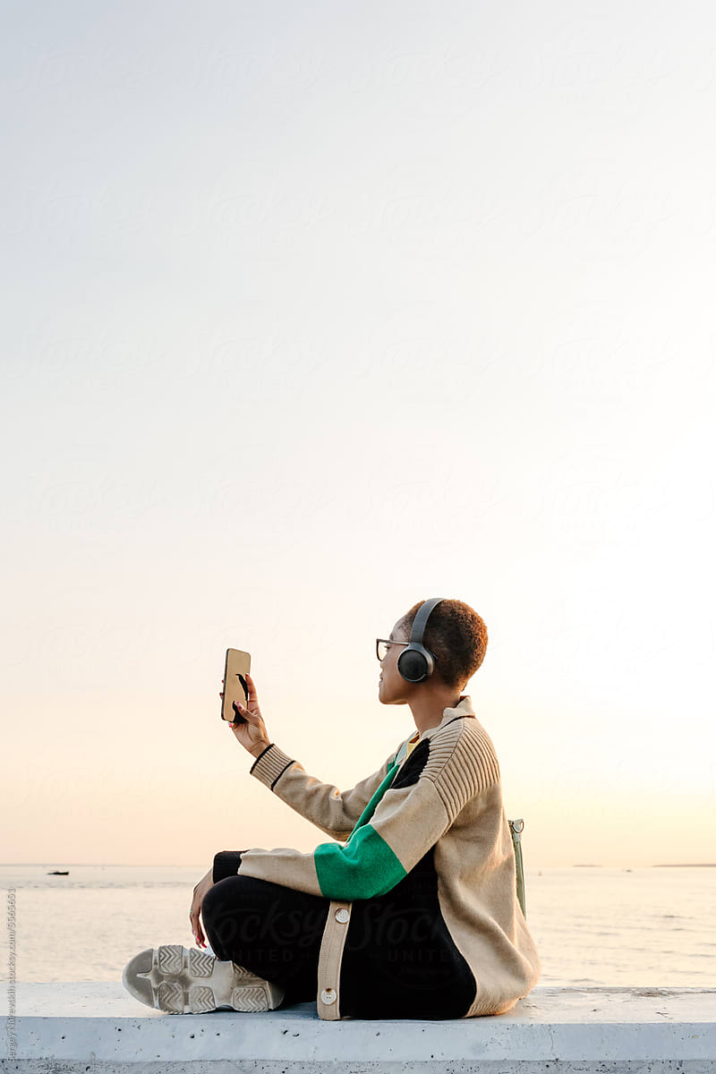 Woman with headphones taking photo on smartphone
