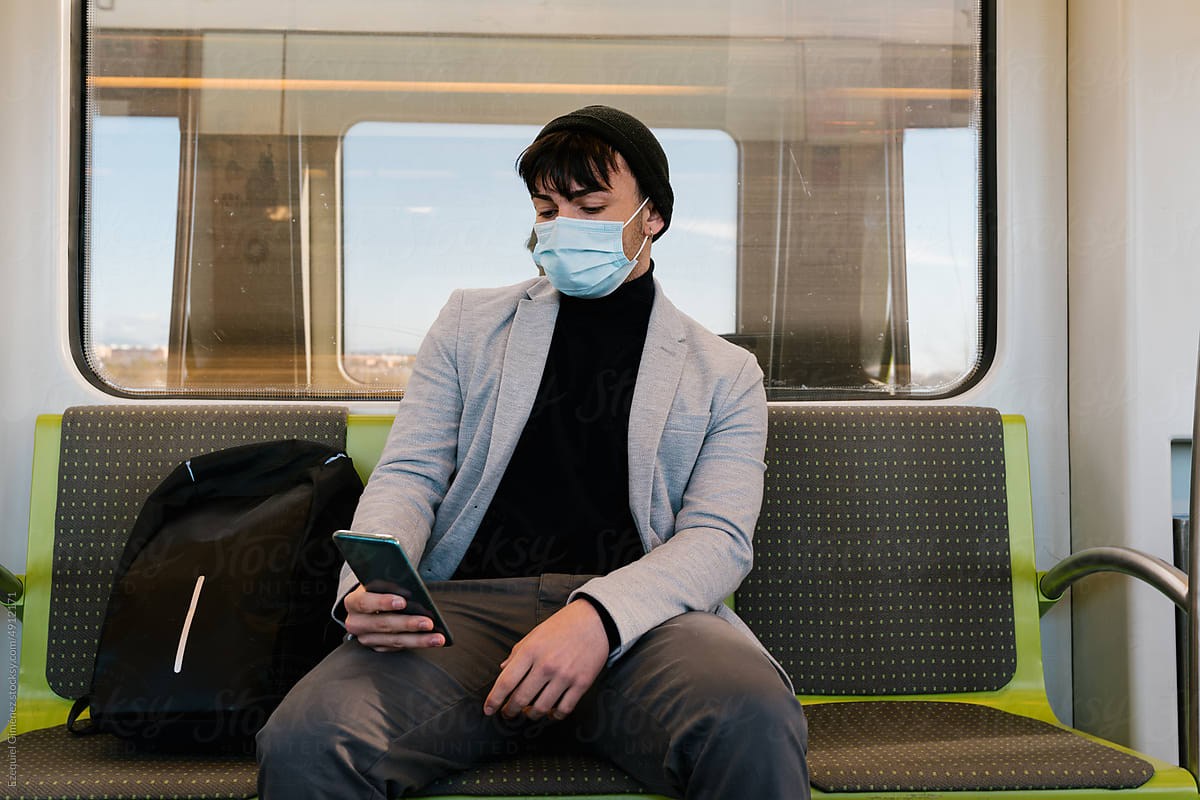 Young man in face mask using smartphone