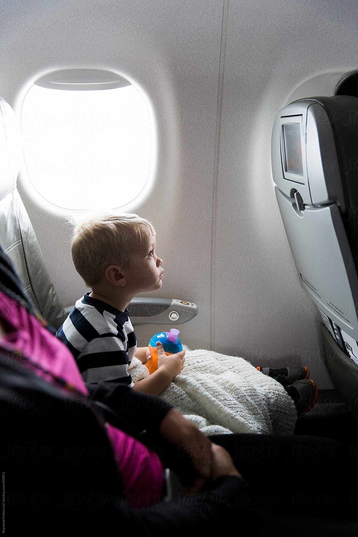 Portrait of young boy sitting in plane seat with sippy cup
