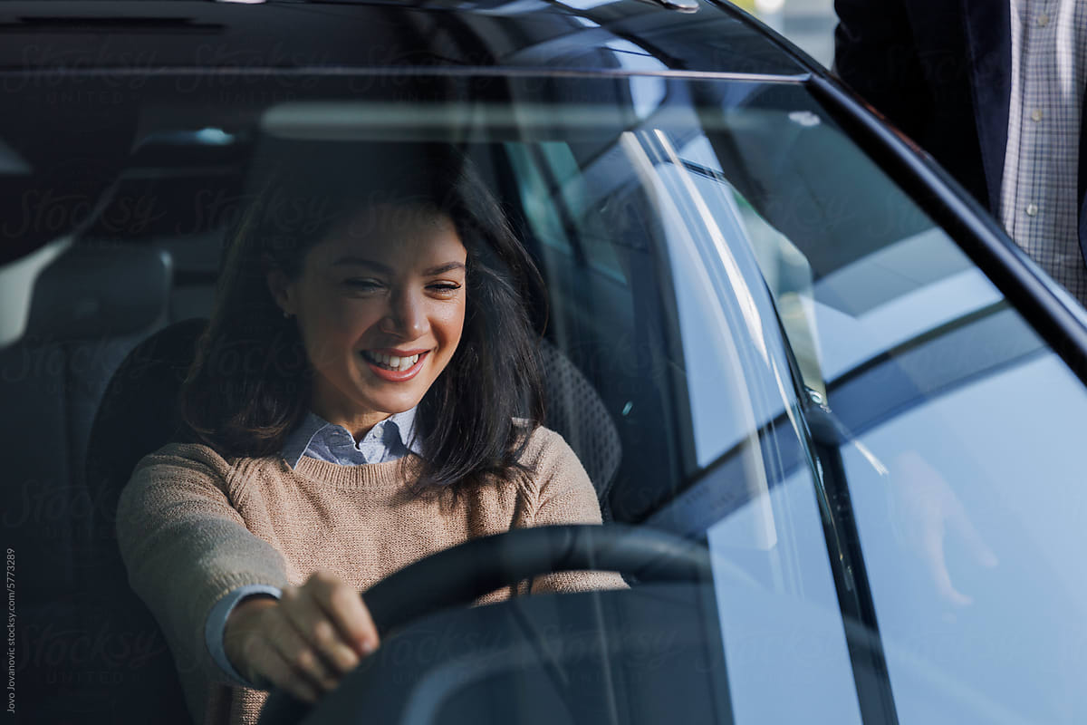 Excited happy woman sitting in new car at dealership