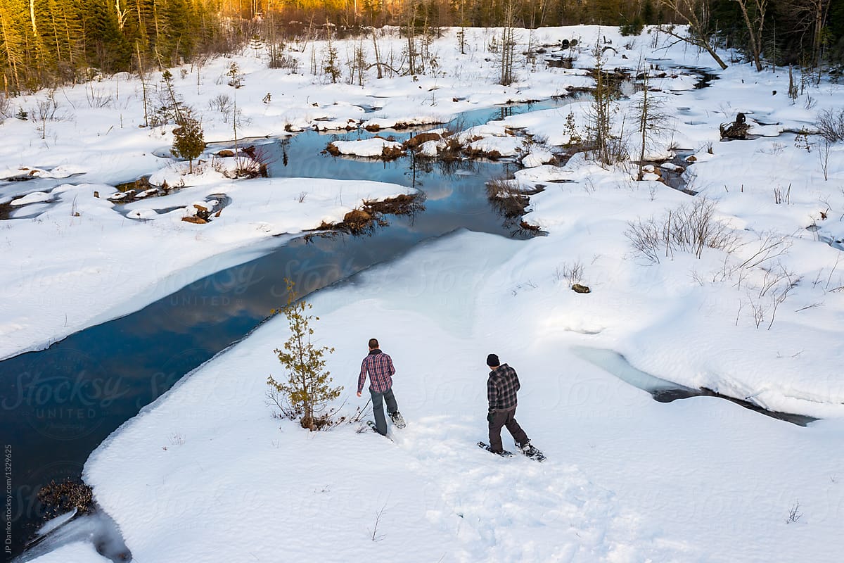 Two Men Snowshoeing Through the Woods on Winter Day