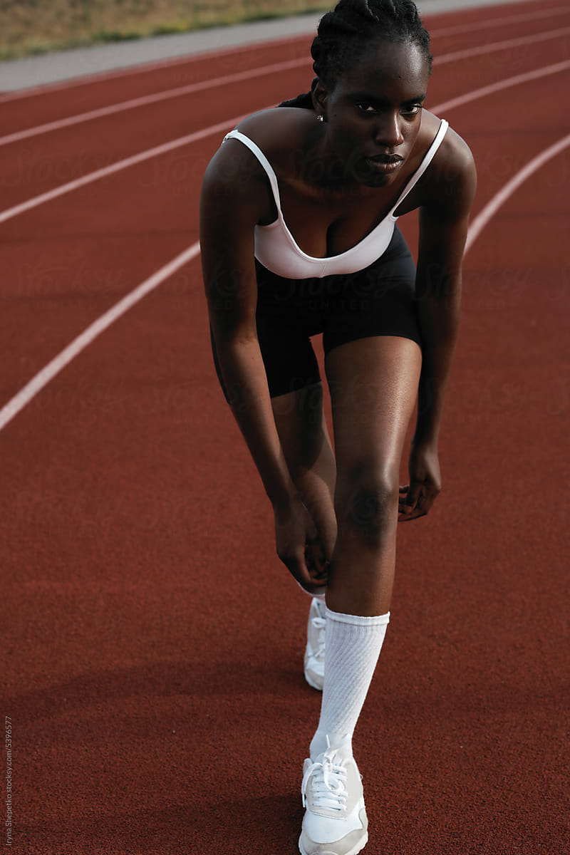 African American woman running on stadium track