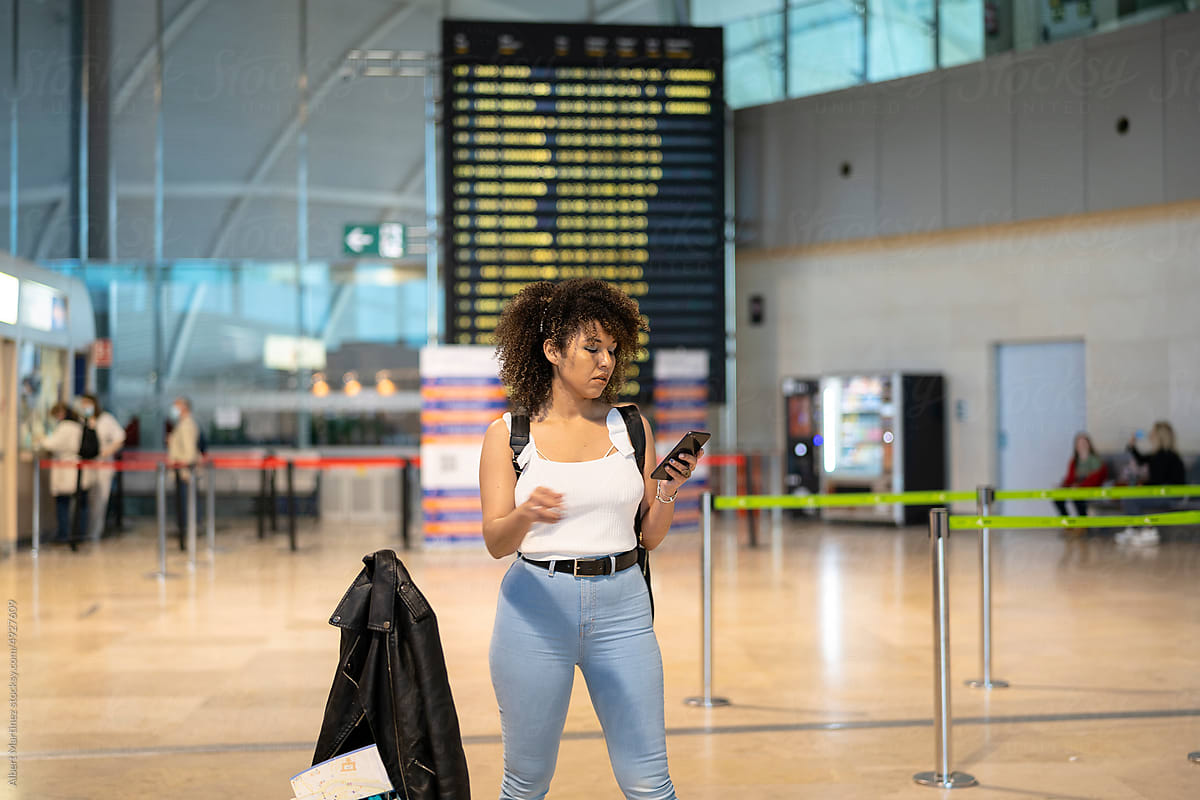 Black woman using smartphone in airport