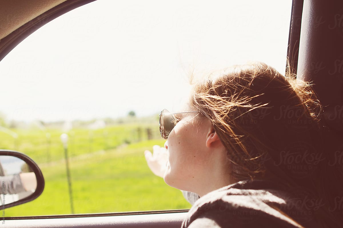 A teenager leans out the open window with her hand out the window