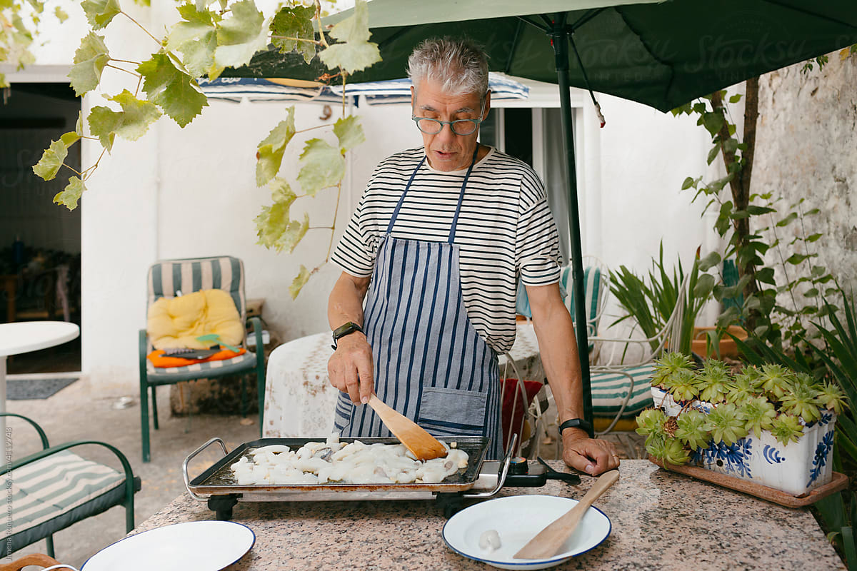Mature man cooking in outdoor electric griddle