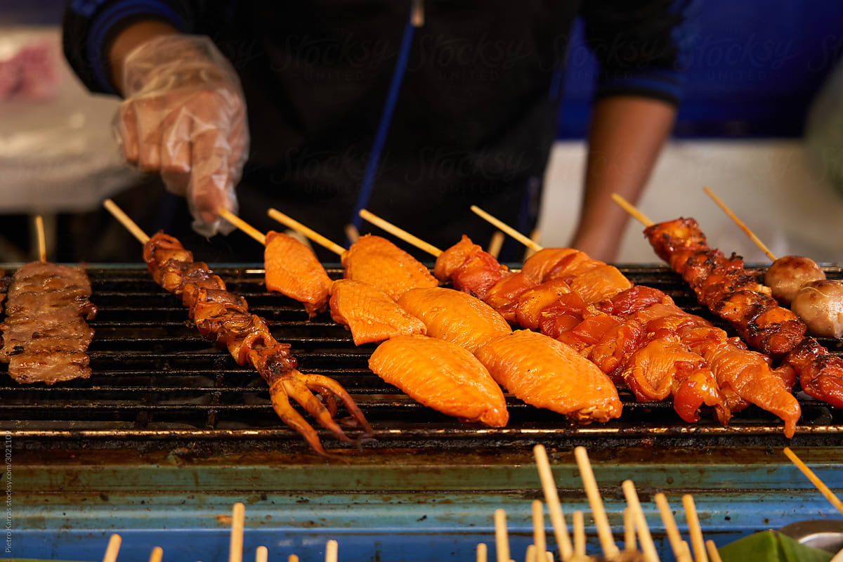 Crop man turning skewers with seafood on grill