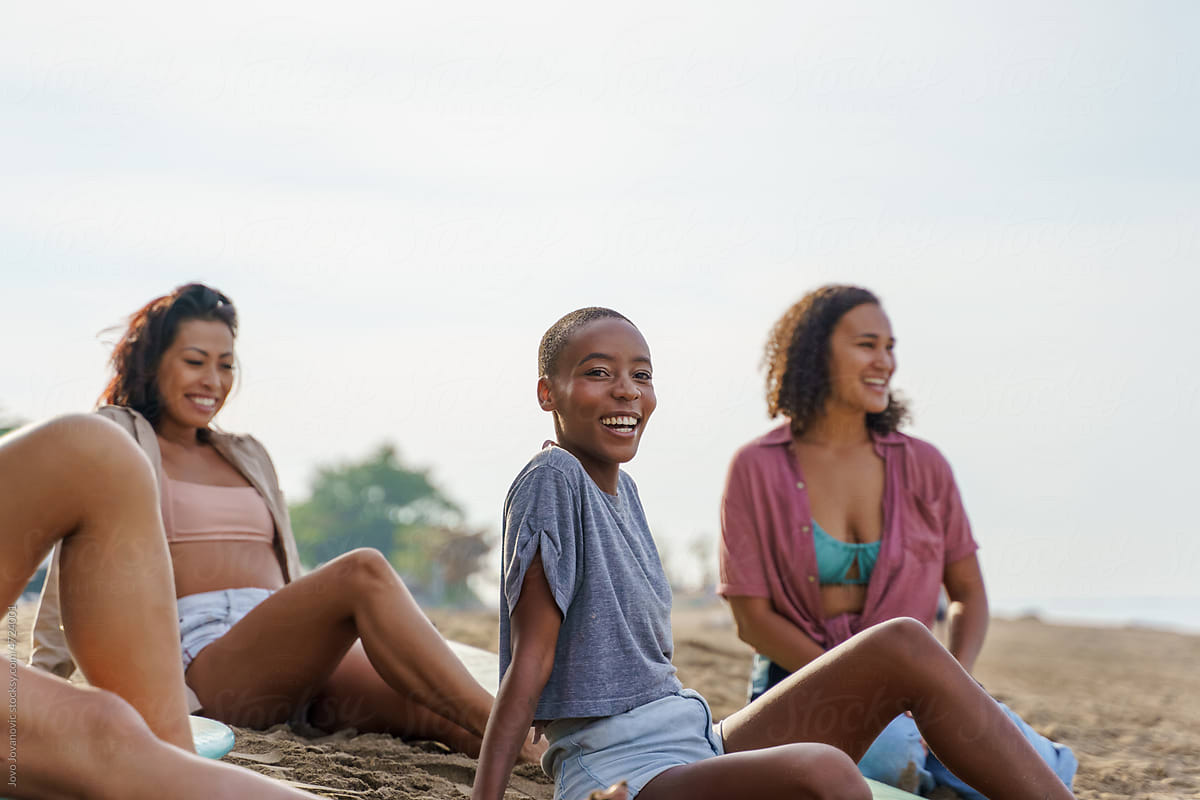 Black woman smiling at camera while hanging out with friends at beach