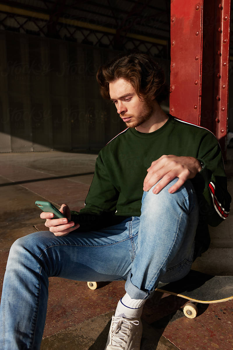 Young trendy skater using smartphone