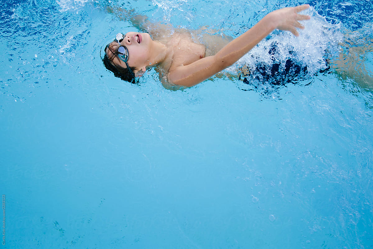 Twelve year old swimmer doing backstroke in lap pool