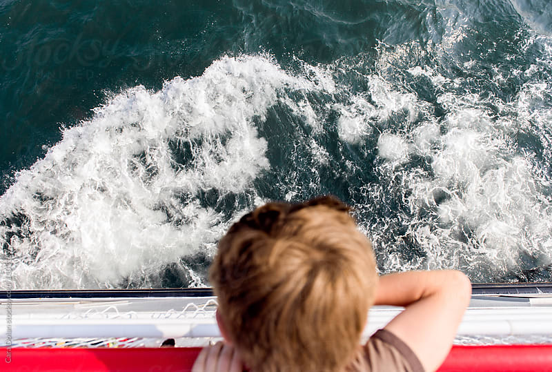 Boy looks down into the water from the ferry