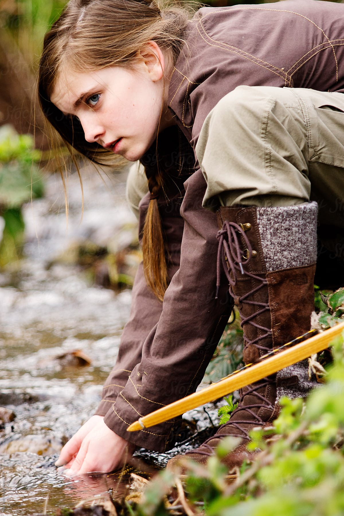Young girl stopping to get water from a stream with her hands.