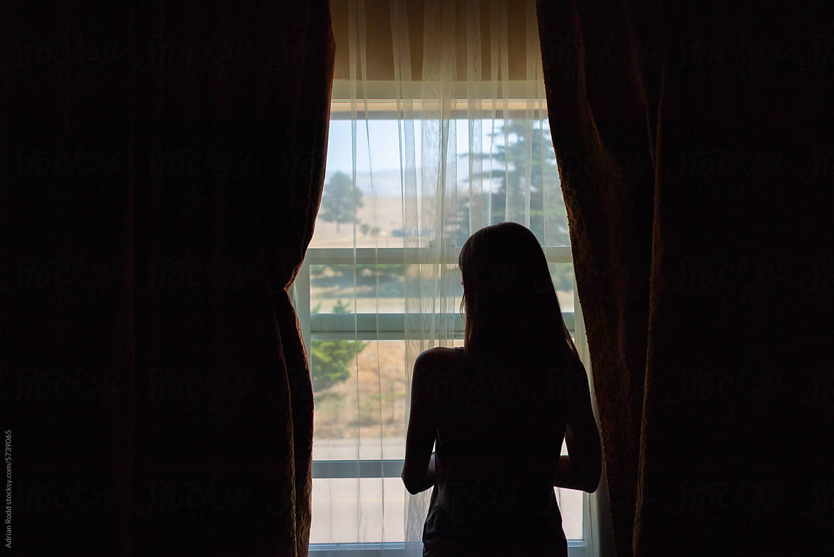 The silhouette of a woman leaning out of a window