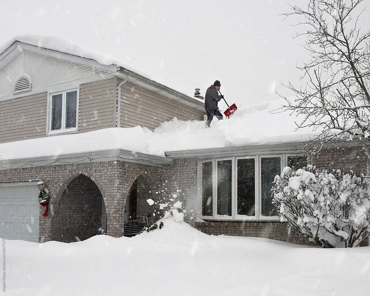 Man Shoveling Snow from Roof of Home
