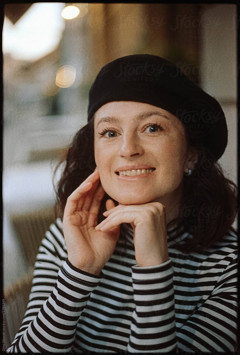 A film portrait of an attractive smiling European woman in a beret