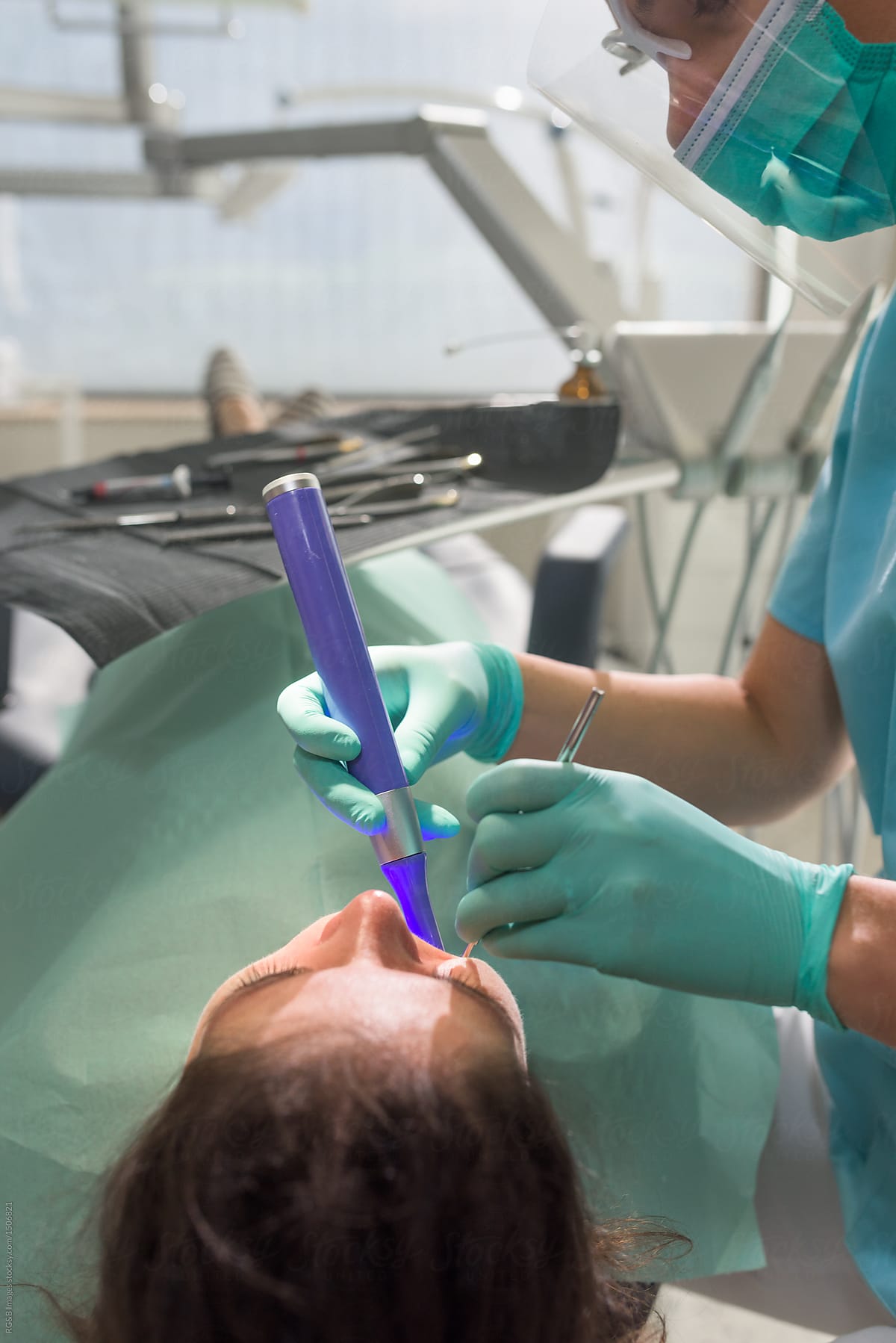 Female orthodontist using ultraviolet light handpiece