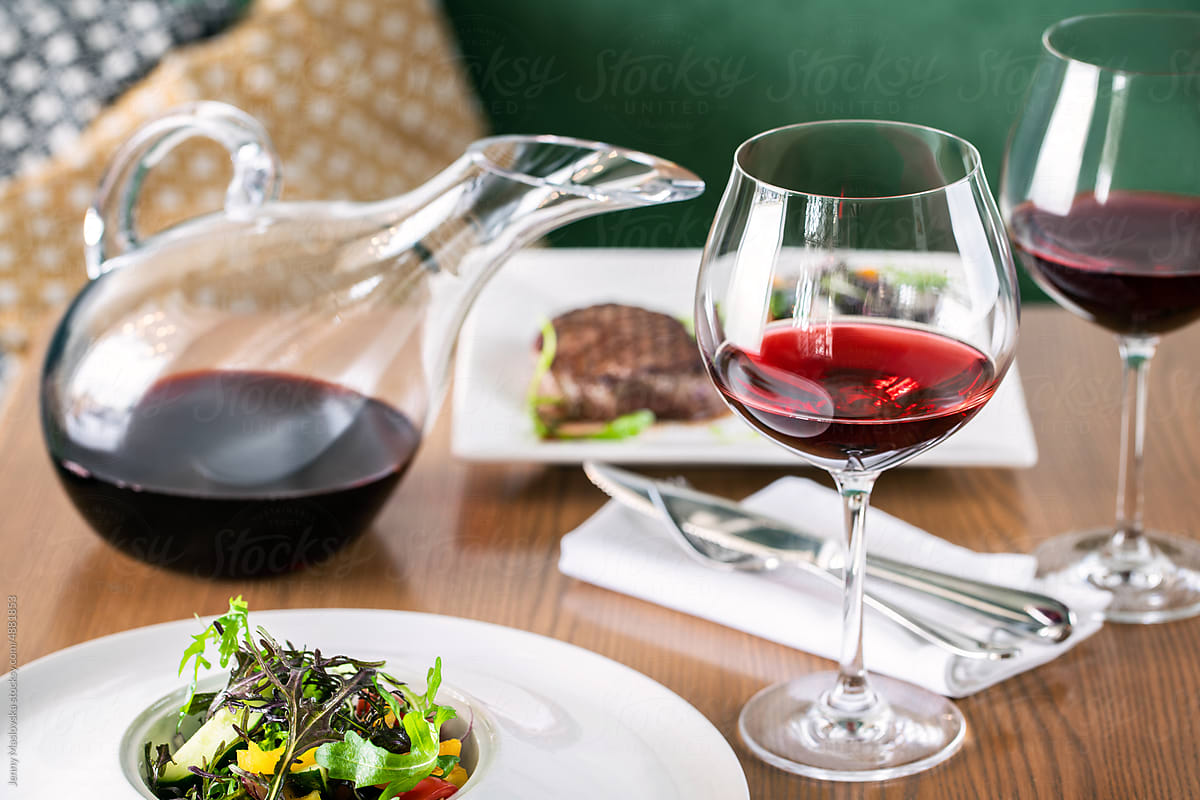Steak and  Red wine served in a decanter and wine glasses