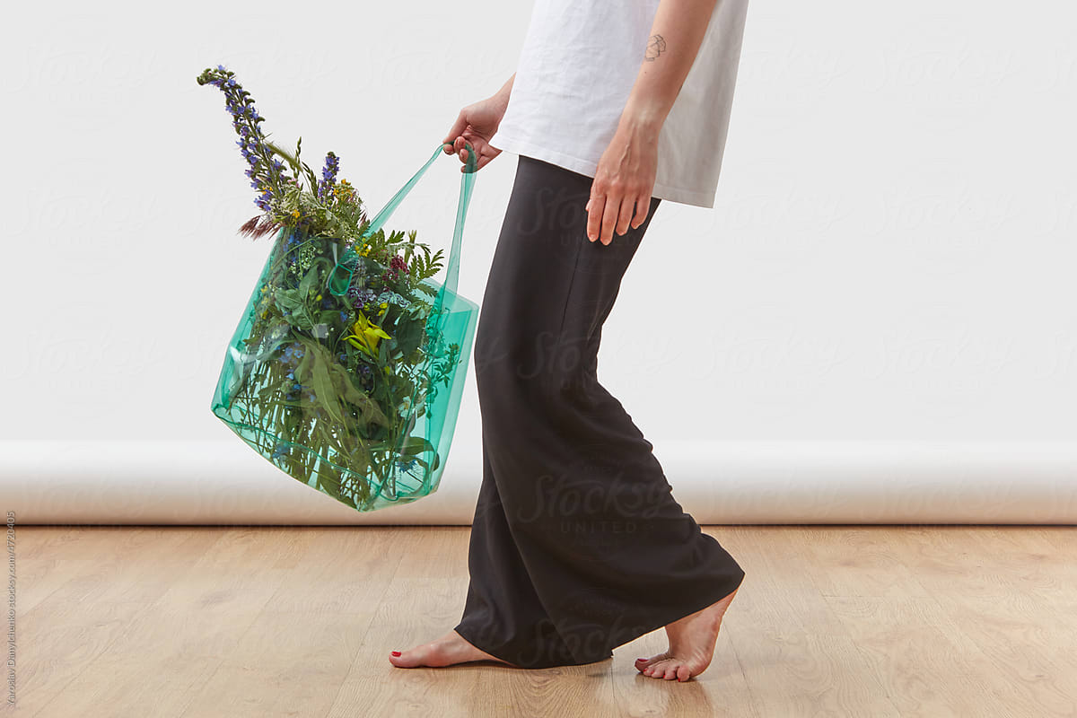Person walking with flowers in recycled bag.