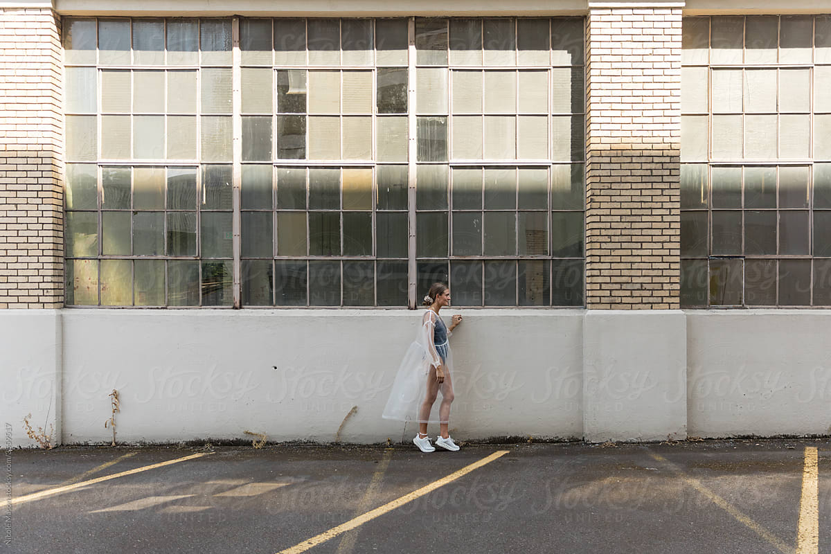fashionable woman standing by huge warehouse windows