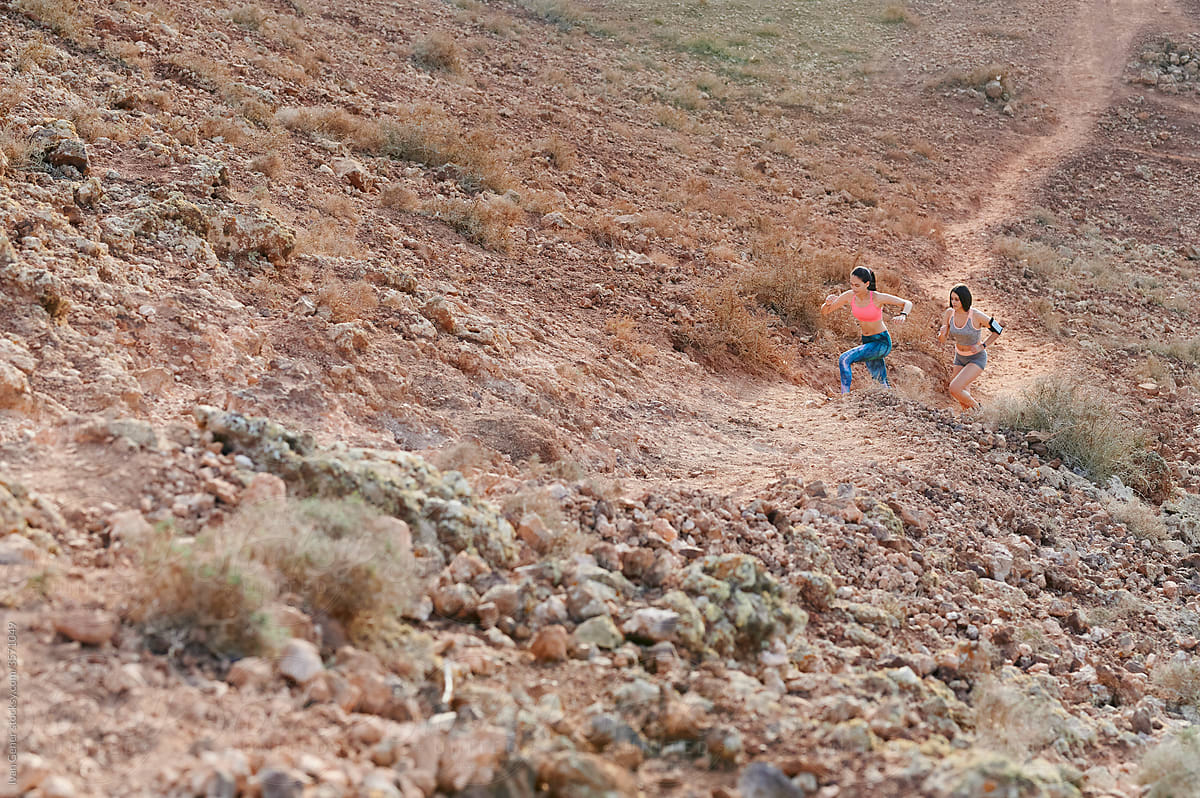 Women running up a trail in rugged terrain