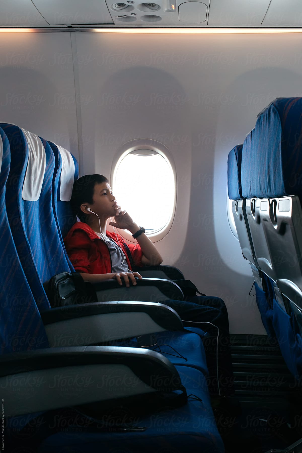 Young plane passenger sitting alone and enjoying the in-house movie