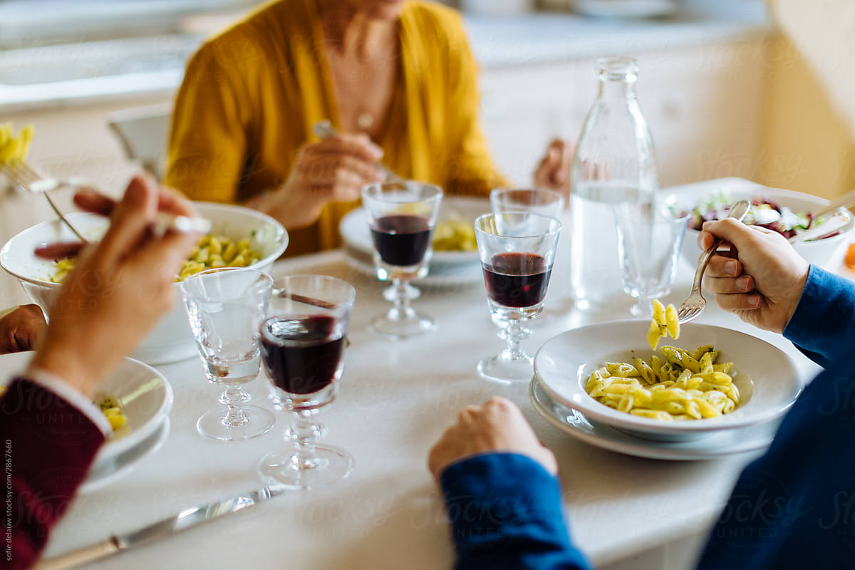 Unrecognizable family having pasta and wine for dinner