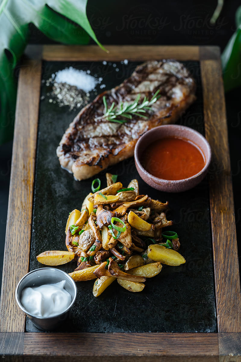 Grilled beef steak with baked potatoes and sauces