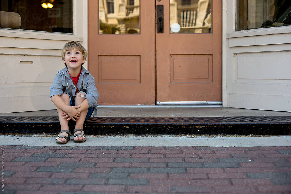 Young boy sitting on store stoop