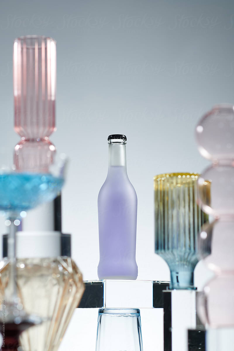 Soda pop glass bottle on a light background with wine glasses