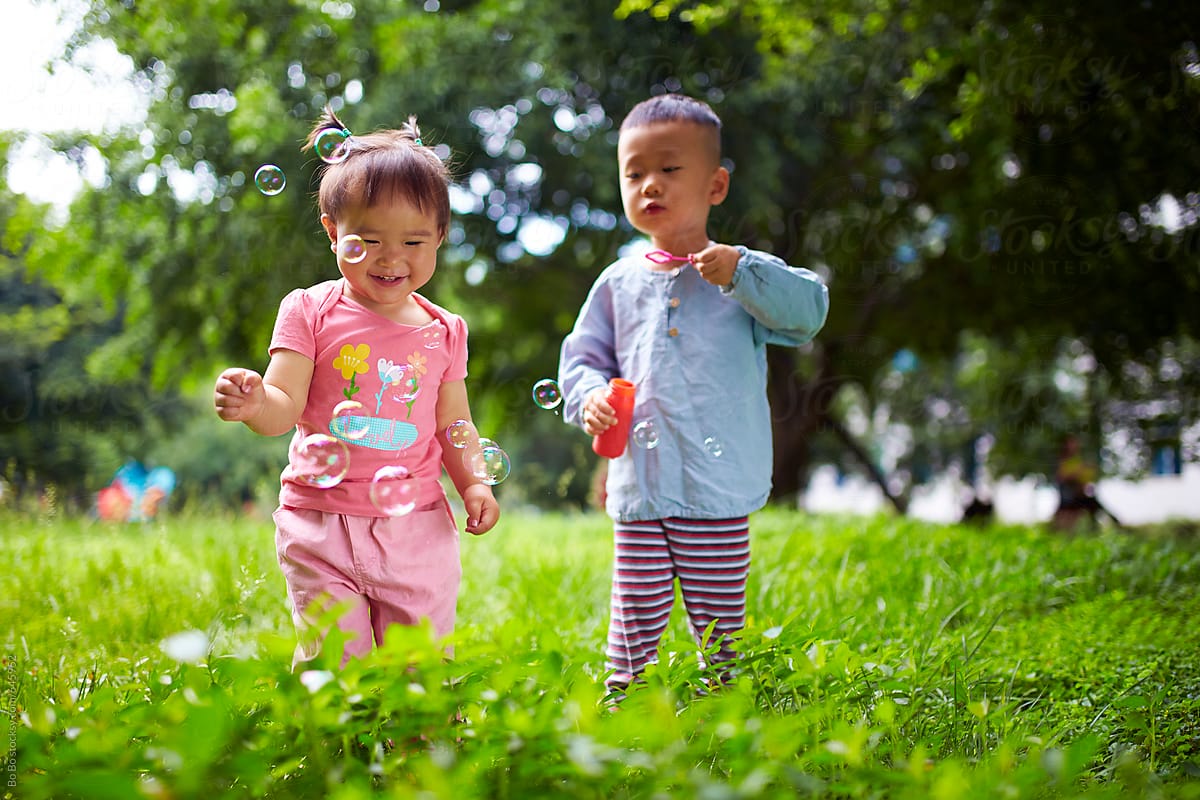 Two Happy Asian Kids Playing In The Park by Bo Bo