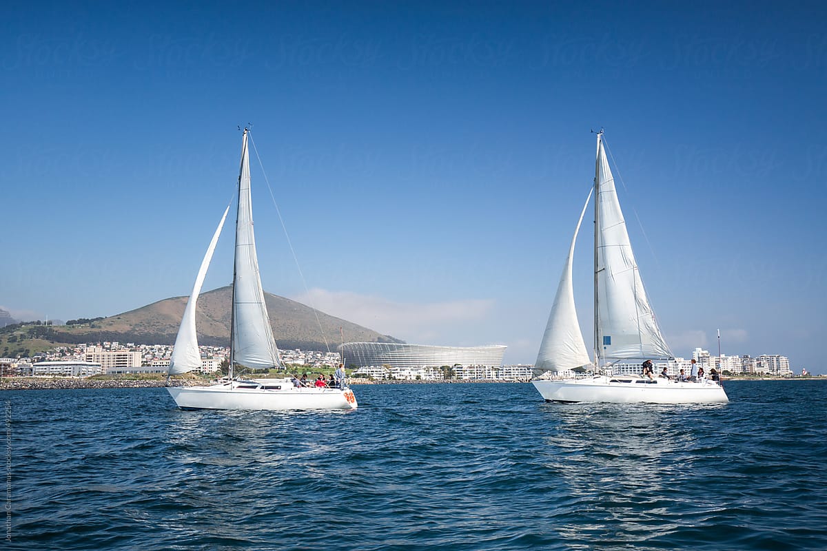 cape town sailboat yachts with sails up on ocean adventure with greenpoint stadium and city in background