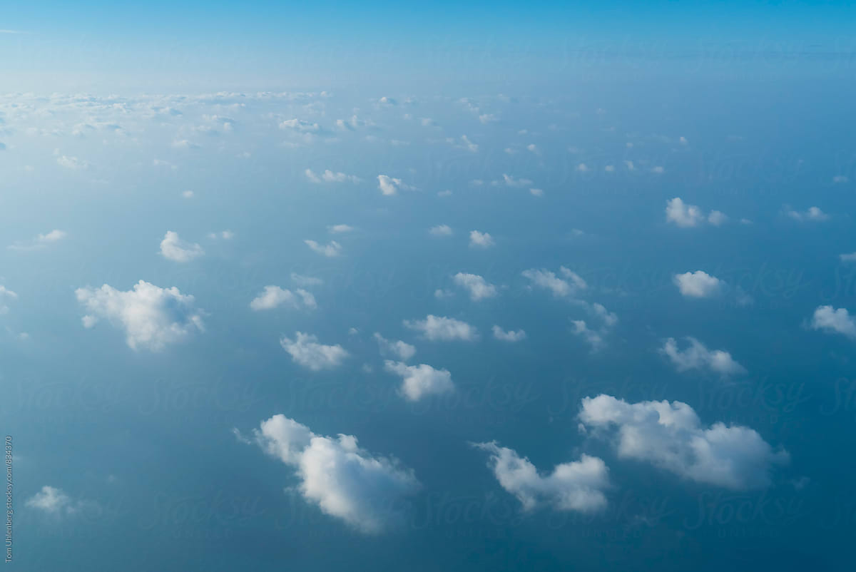Flying above Small, Fluffy Clouds and a Blue Ocean