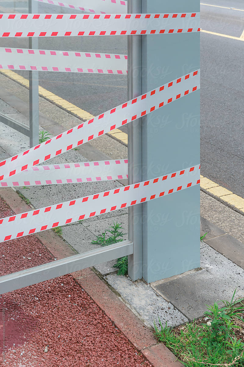 A bus stop wrapped around a barrier tape.