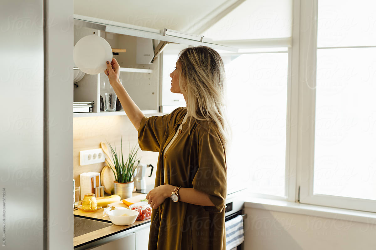 Woman Taking A Plate From The Cupboard