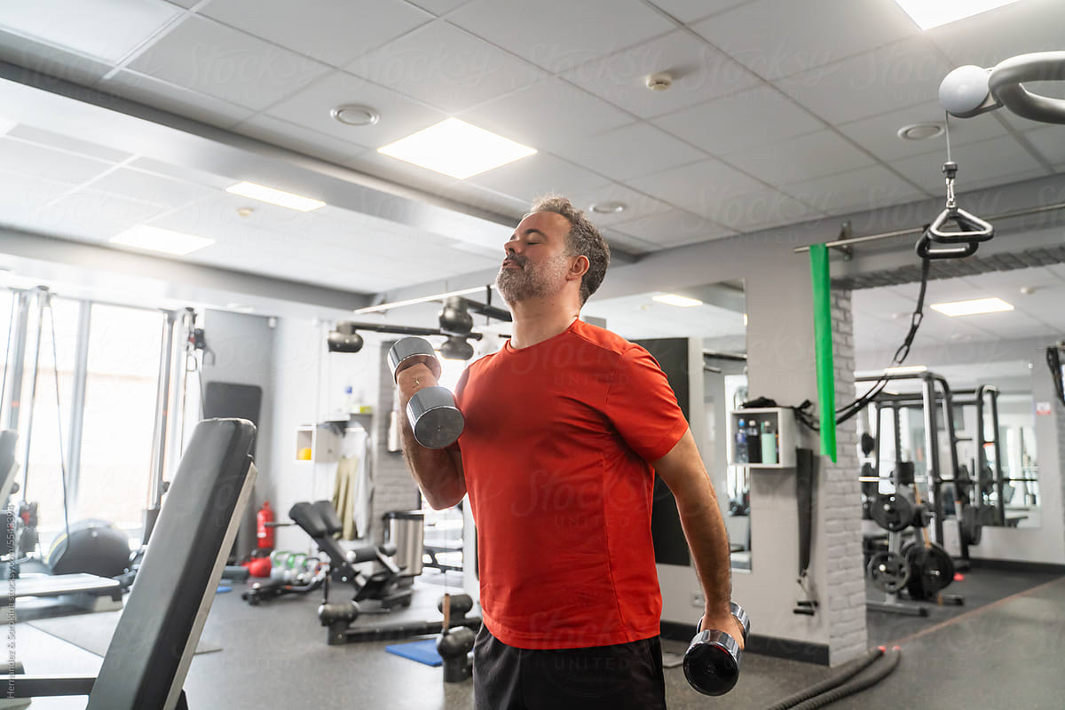 Man Exercise Using Dumbbells At Gym