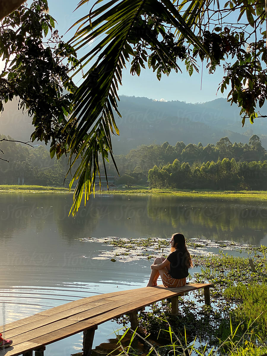 travel woman sitting by a lake