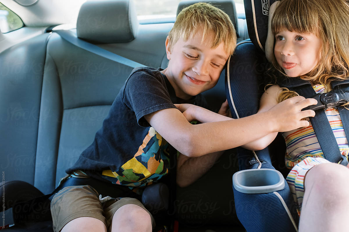 smiling little brother giving his sister a hug in the car