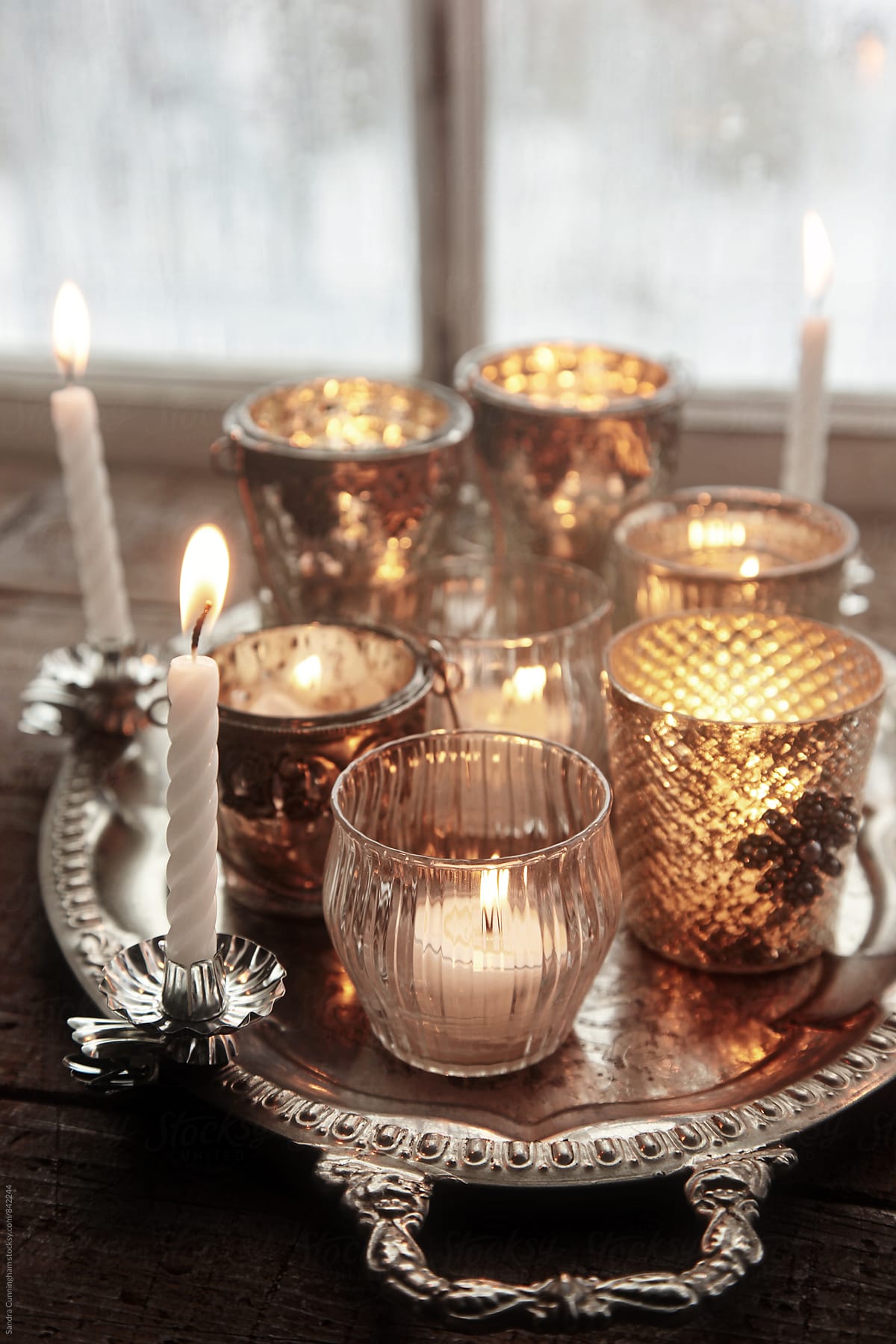 Closeup of silver votive candles in front of window