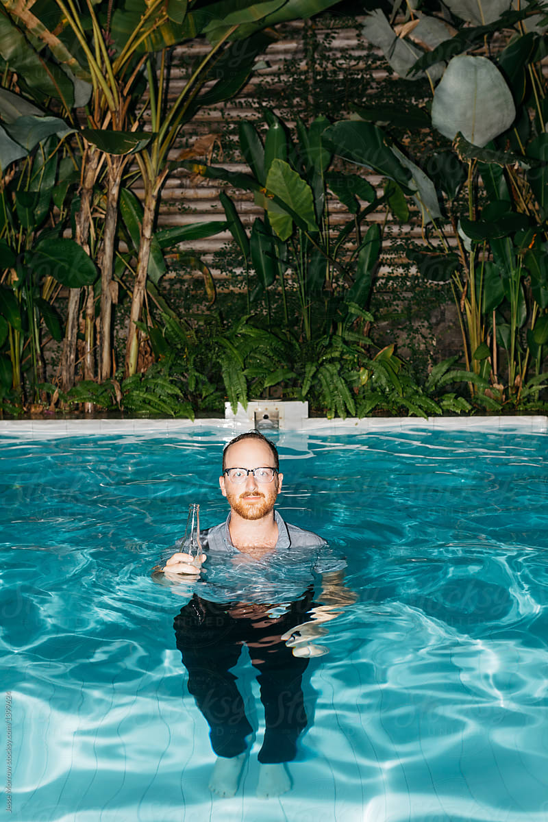 Young Fully Clothed Male Drinks A Beer While Swimming In A Pool During 